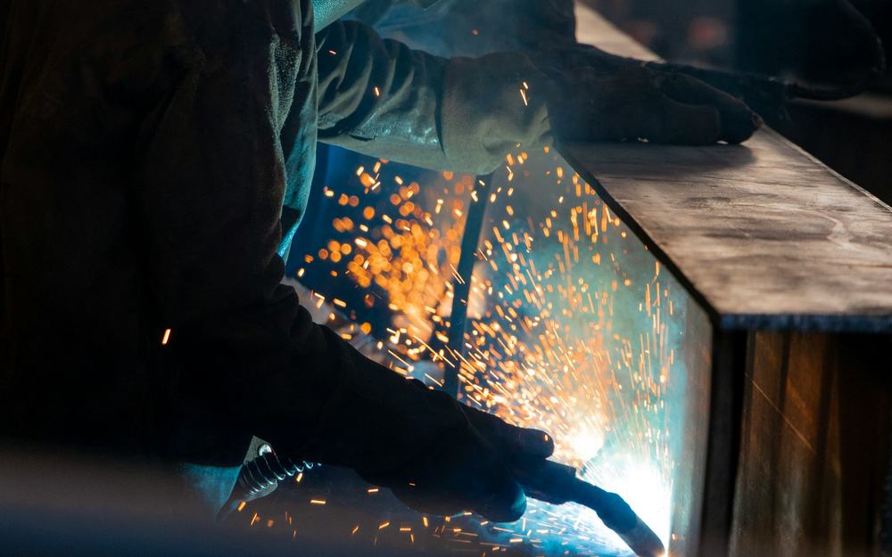Worker in full personal protective equipment welding in an industrial workshop